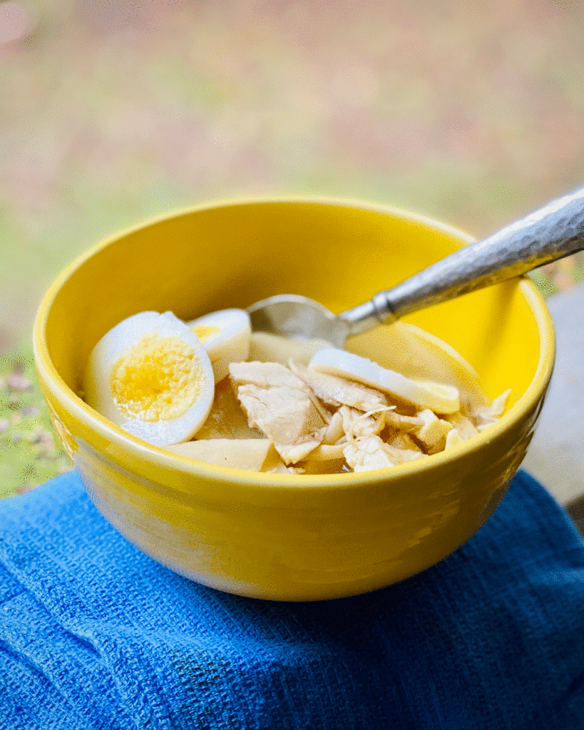 Chicken and dumplings in a yellow bowl | Photo by A Cook and Her Books