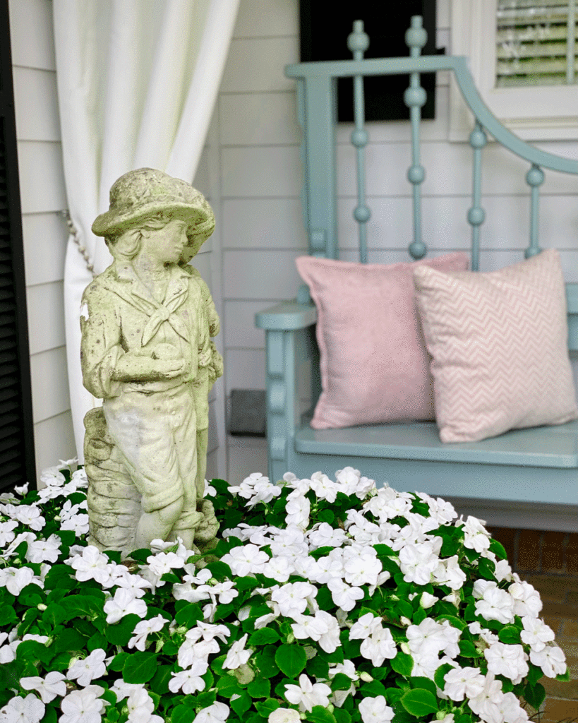 Female statue surrounded by white impatiens