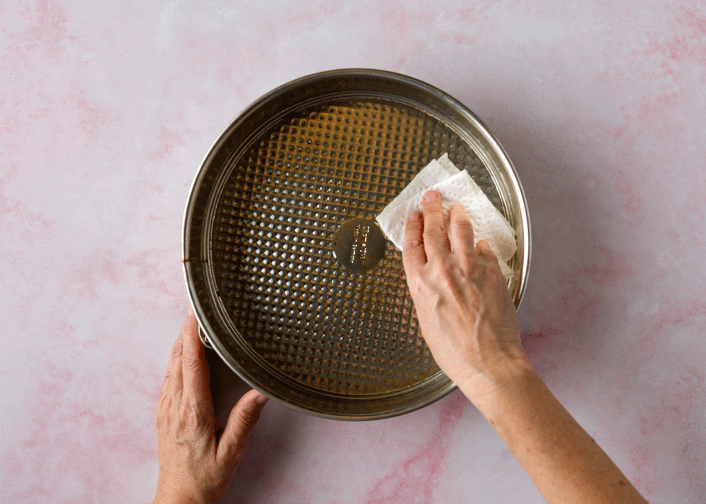 Baker greases a springform pan with vegetable oil