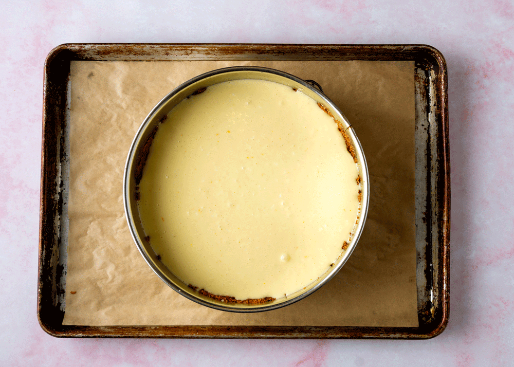 Cheesecake filling in a springform on a parchment lined pan