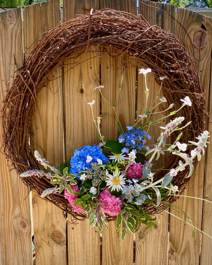 Wreath with spring flowers on garden fence