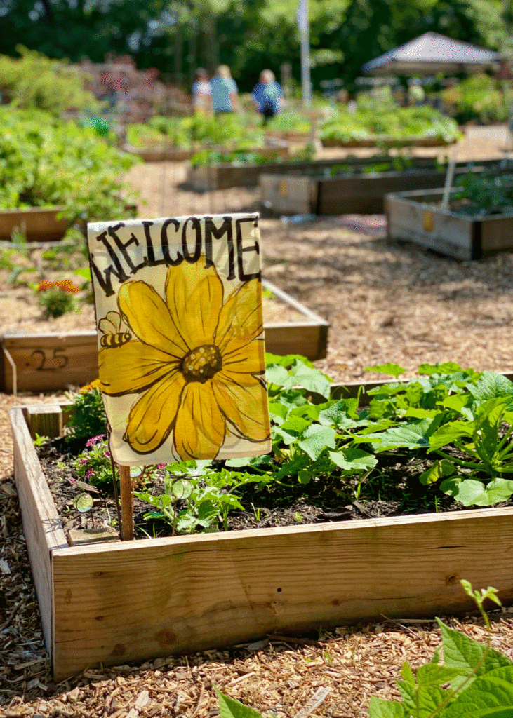 Welcome sign with yellow flower in a raised garden bed