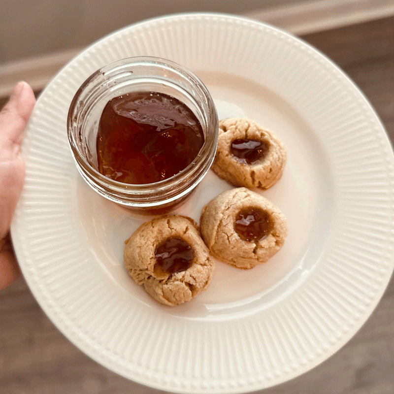 Jelly in a jar on a plate with thumbprint cookies