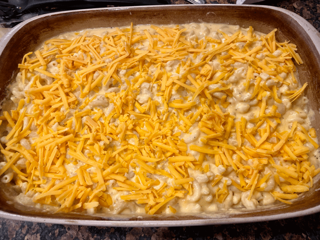 Grated Cheddar cheese on top of creamy macaroni in a casserole