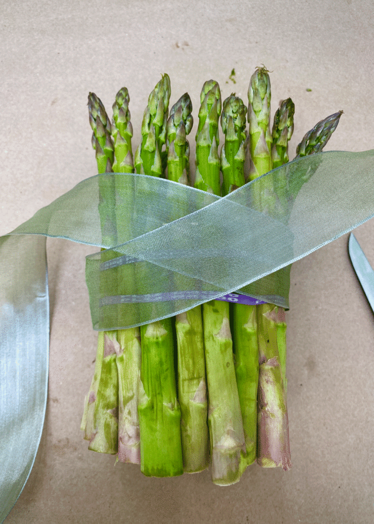 A ribbon crossed over the rubber band on the asparagus bundle