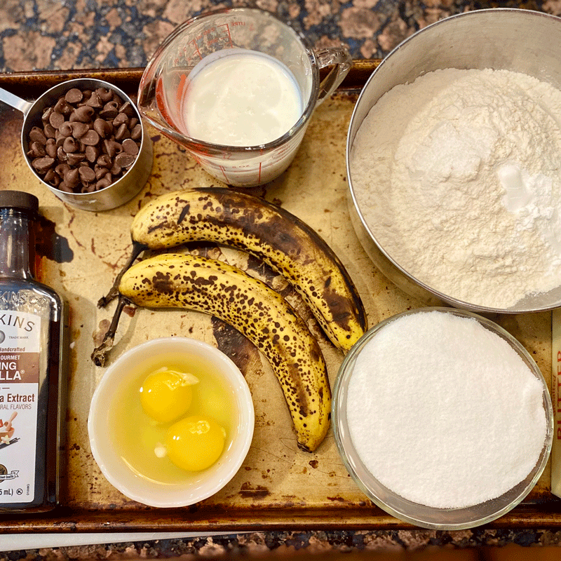 Ripe bananas, eggs, flour, buttermilk and sugar on a tray