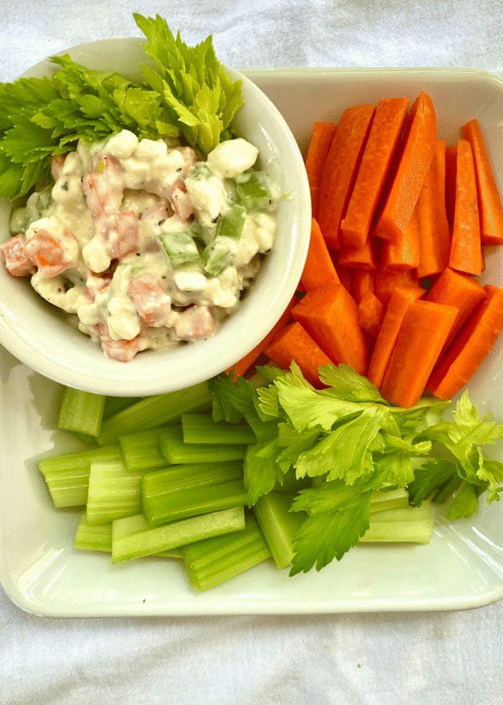Bowl of cottage cheese dip with celery and carrot sticks