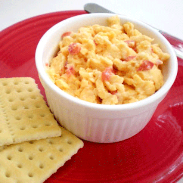 Pimento cheese in a bowl on a red plate with crackers