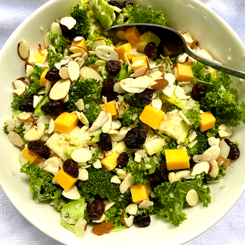 Broccoli salad with Cheddar chunks and dried cranberries in a white bowl
