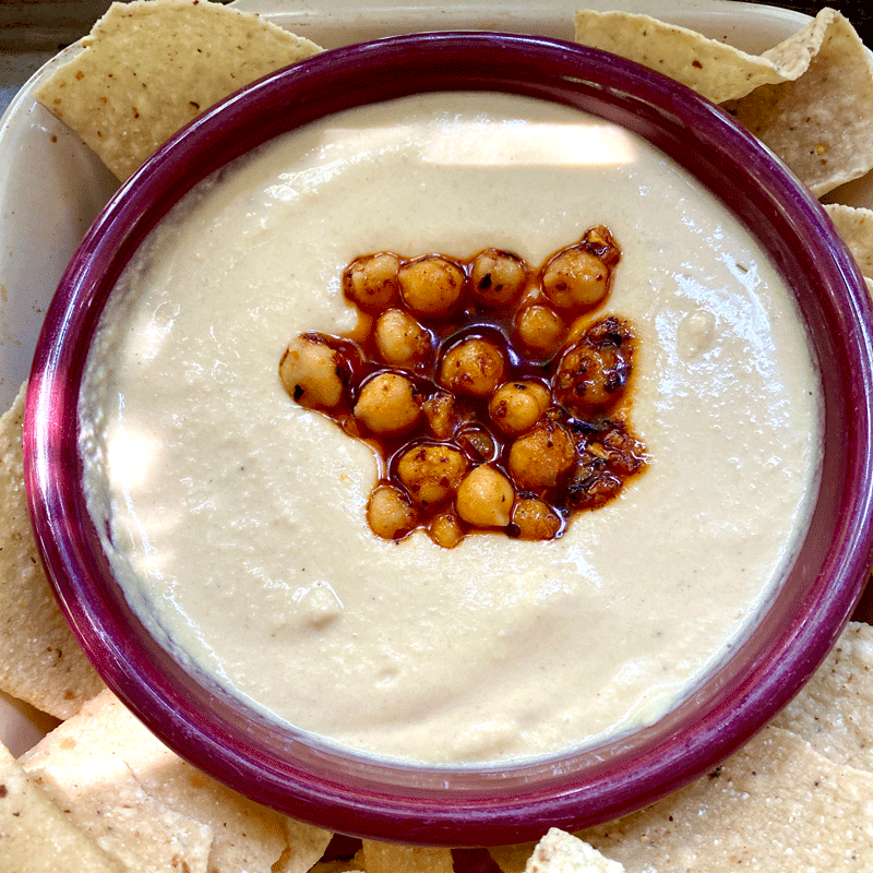 A bowlful of hummus with chickpeas in the center