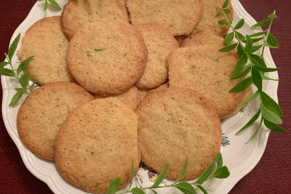 Lemon verbena cookies on a plate with sprigs of lemon verbena herbs