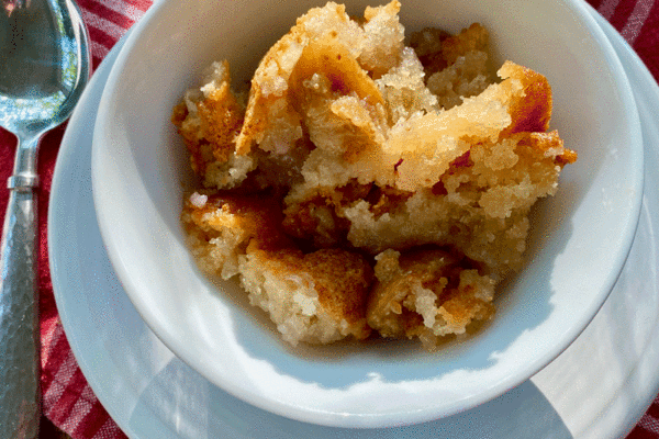 Fig cake crumbled in white bowl on plate with a spoon