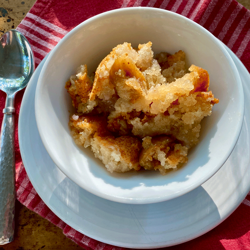Fig cake crumbled in white bowl on plate with a spoon