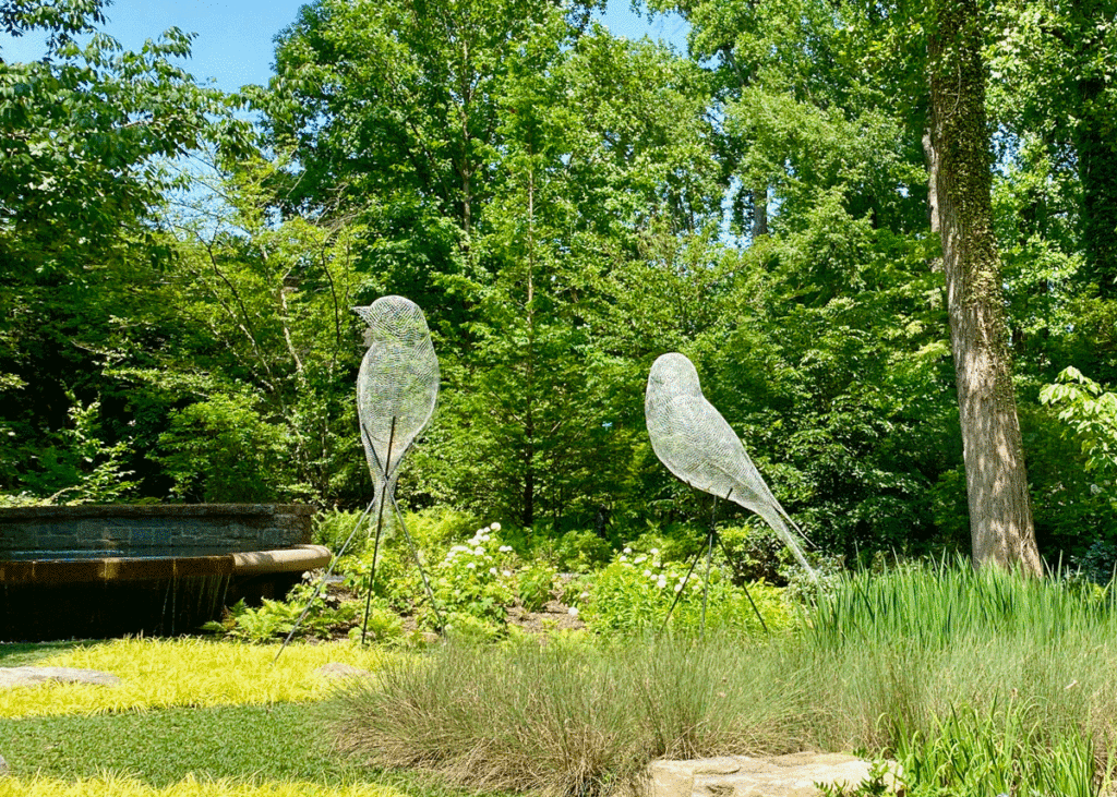 Two bird sculptures in a garden meadow
