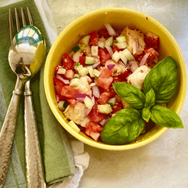 Tomato bread salad with basil in a yellow bowl