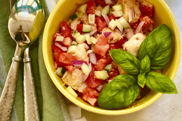 Tomato bread salad with basil in a yellow bowl