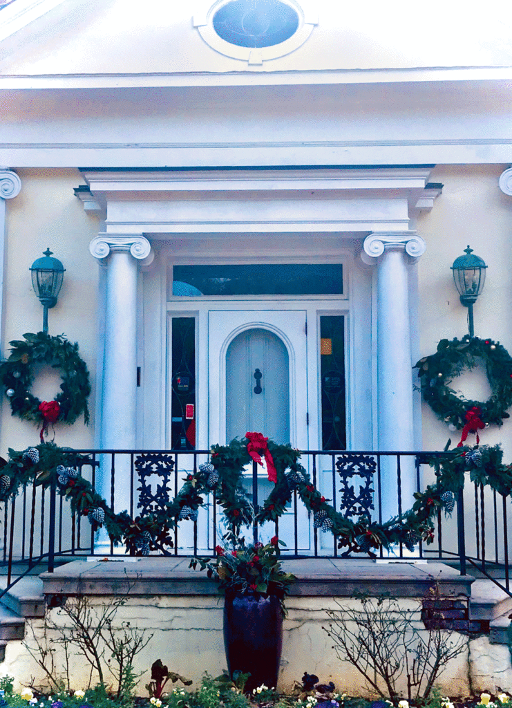Classical home exterior decorated with evergreen wreaths and garland