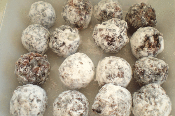 Rows of date candies covered in powdered sugar on a plate