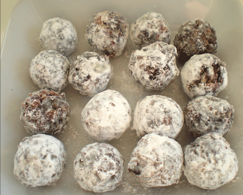 Rows of date candies covered in powdered sugar on a plate