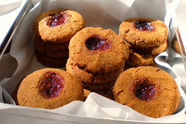 Ginger cookies with raspberry jam stacked in a cookie tin