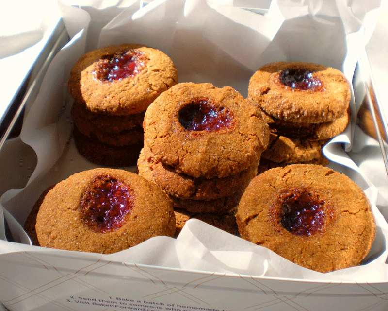 Ginger cookies with raspberry jam stacked in a cookie tin
