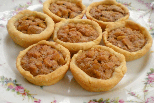 Small nut tassie tarts filled with nuts on a china plate