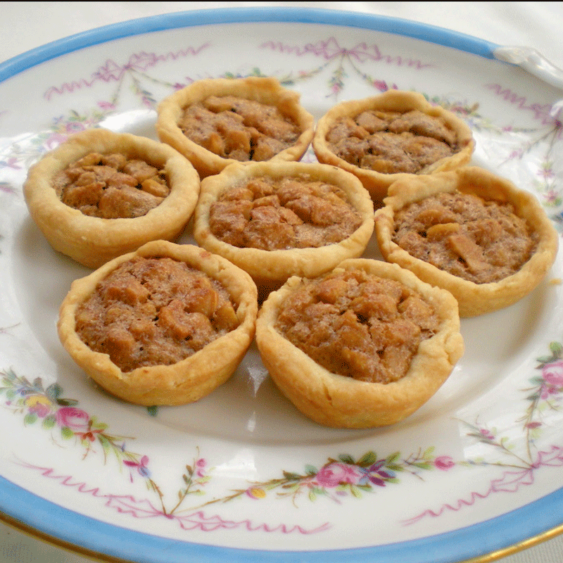 Small nut tassie tarts filled with nuts on a china plate