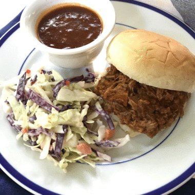 Pulled pork sandwich with barbecue sauce and side of slaw