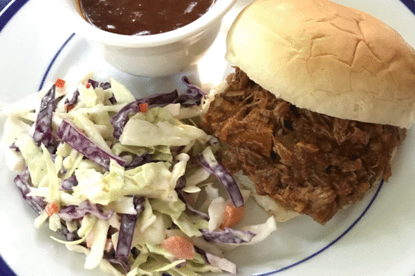 Pulled pork sandwich with barbecue sauce and side of slaw