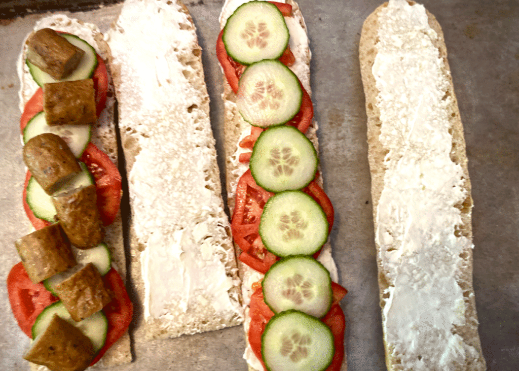 Baguettes sliced in half and spread with cream cheese then layered with sliced tomatoes and cucumbers.