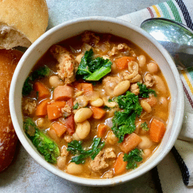 Bowl of vegetable soup with bread and a spoon