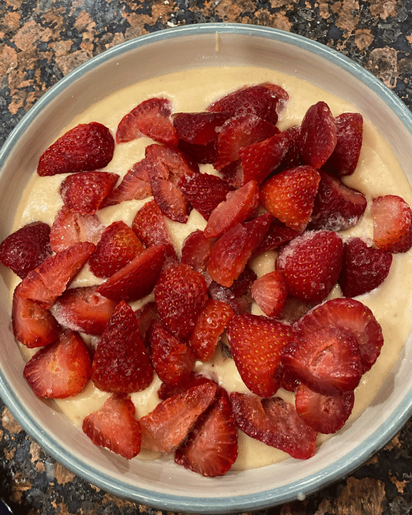Strawberries on spoon cake batter ready for the oven