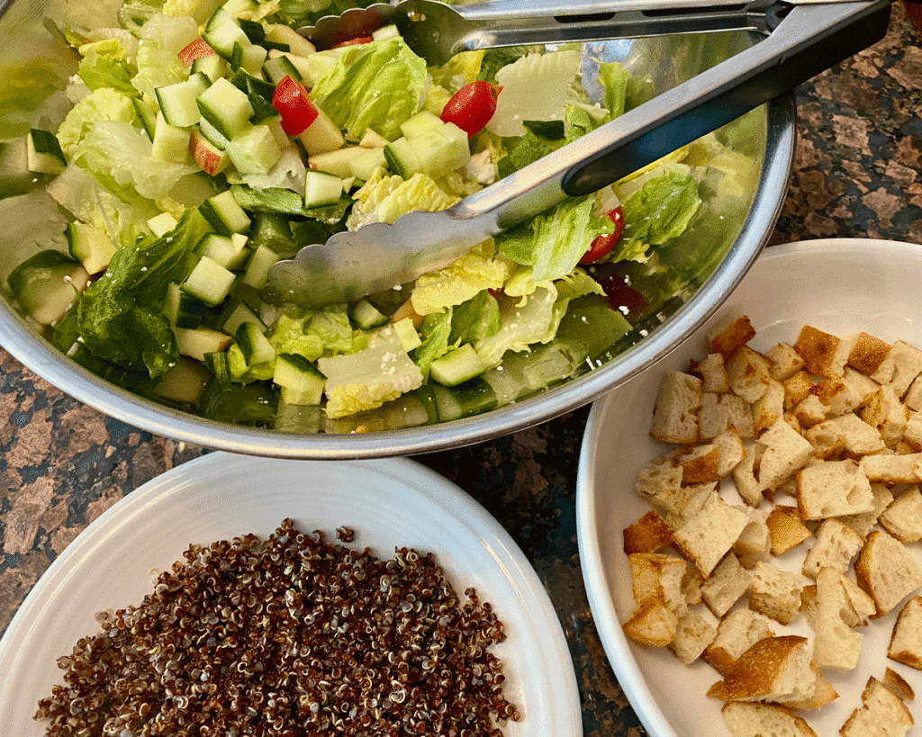 Salad in a bowl with quinoa and croutons in adjacent bowls