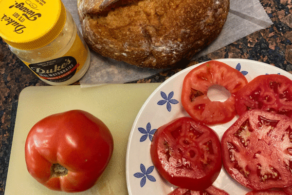 Ingredients for a tomato sandwich on a cutting board in a kitchen