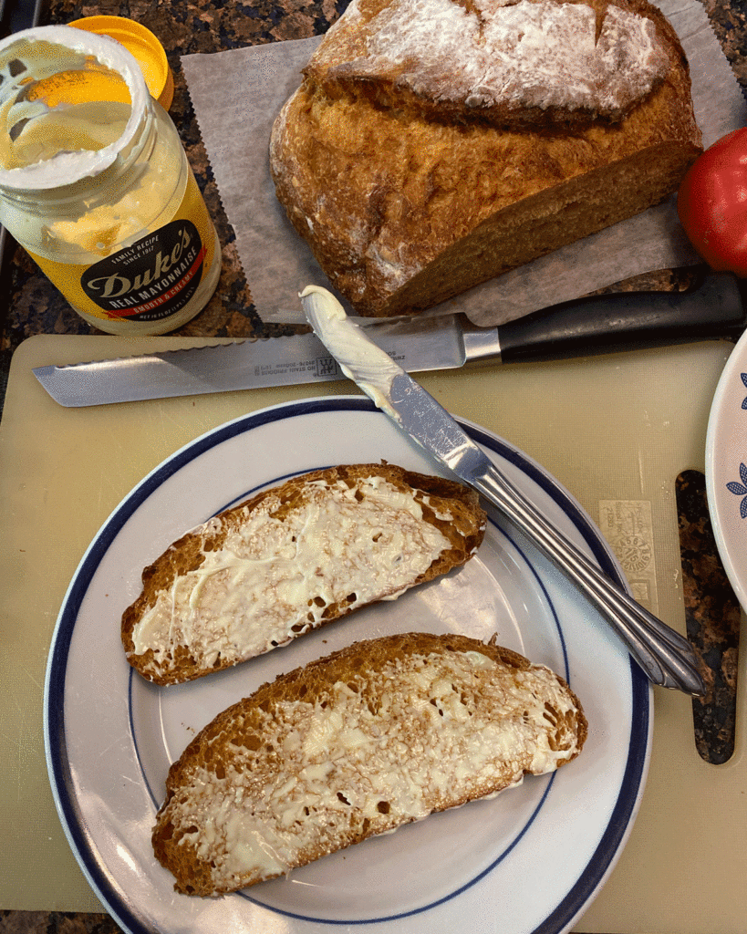 Slices of bread coated with Duke's mayonnaise for a tomato sandwich