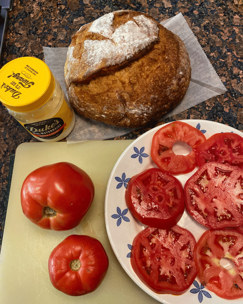 Ingredients for a tomato sandwich on a cutting board