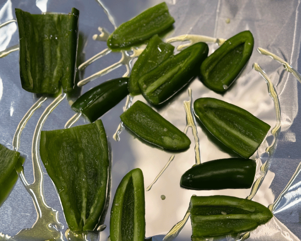 Sliced jalapeno peppers on foil lined baking sheet