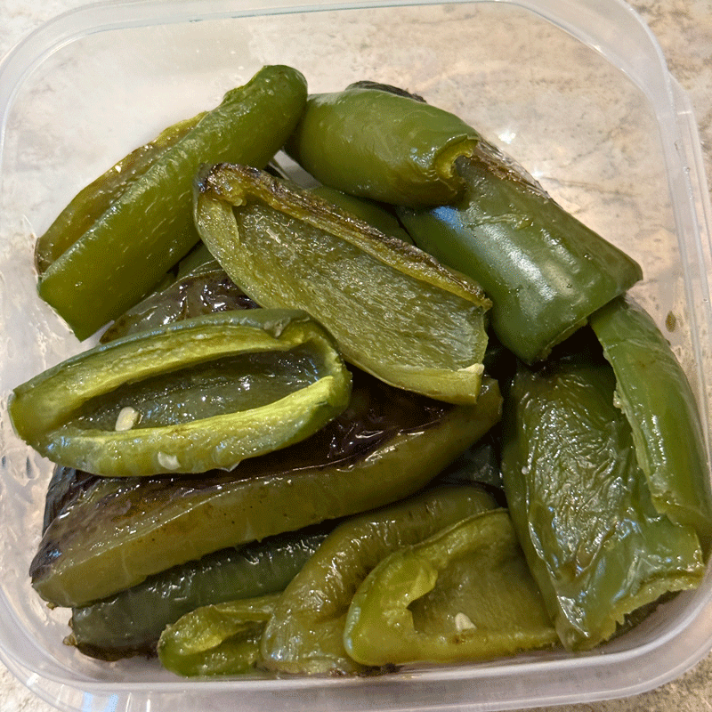 Roasted jalapenos in a plastic freezer container