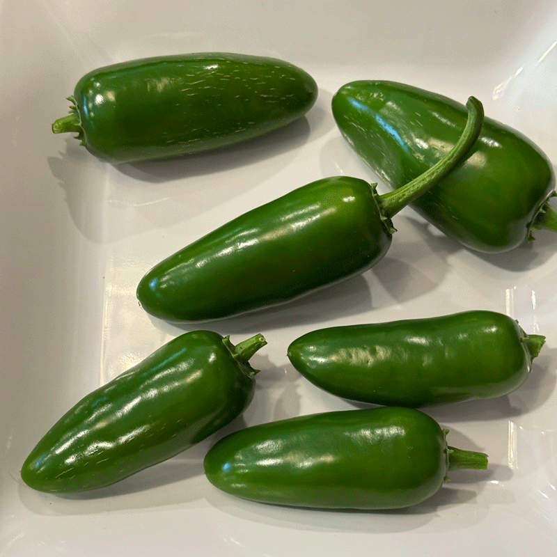 Green jalapeno peppers on a white plate