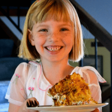 Girl holding slice of carrot cake on a plate