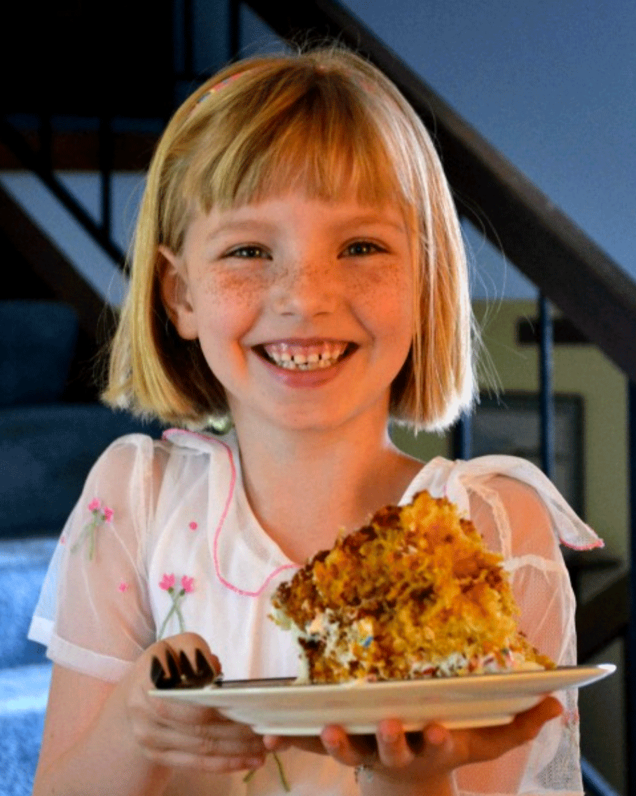 Girl holding slice of carrot cake on a plate