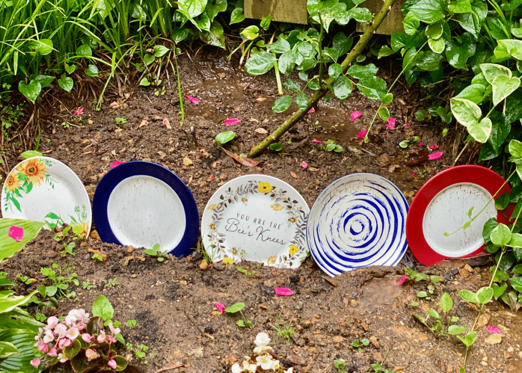A row of unique dinner sized plates in a garden border
