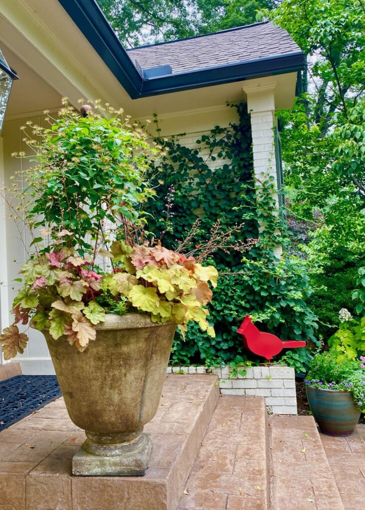 A red bird sculpture and a planter at the entrance to a home