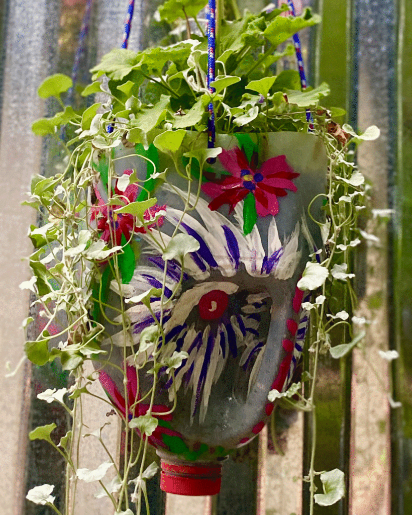 A painted milk jug hanging planter in a garden