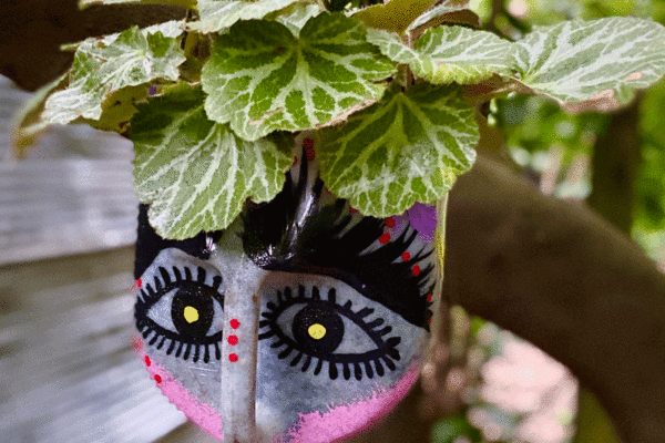 Painted milk jug hanging planter in a garden