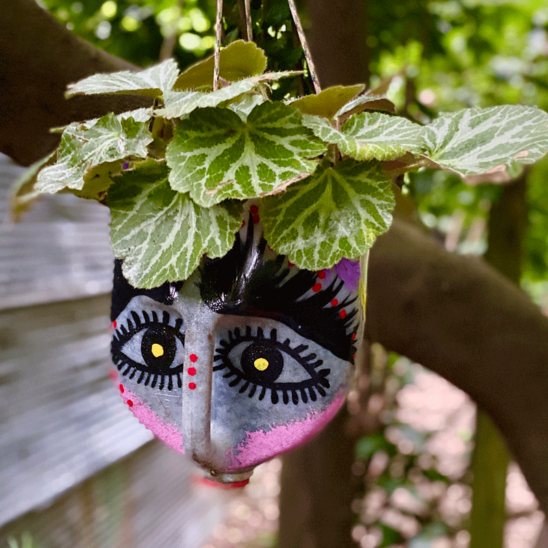 Painted milk jug hanging planter in a garden