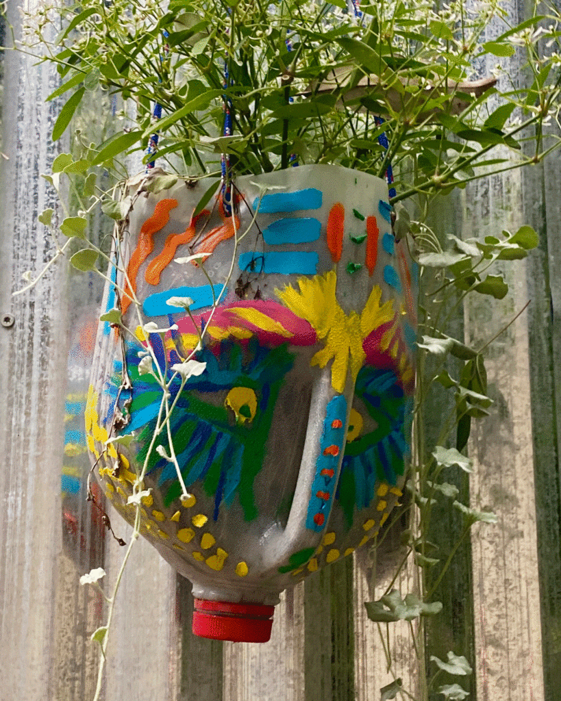 Painted milk jug hanging planter in a garden