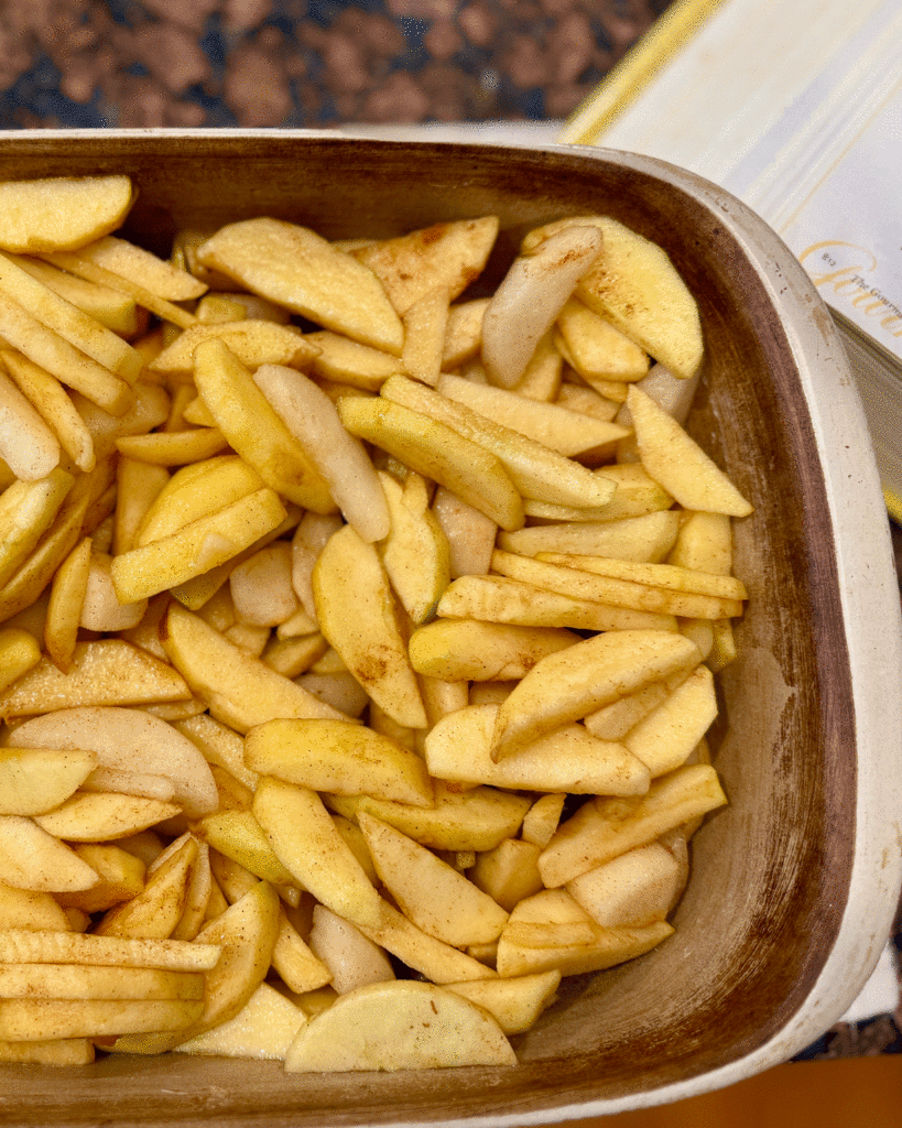 Sliced apples coated with lemon juice, cinnamon and sugar in a buttered casserole dish