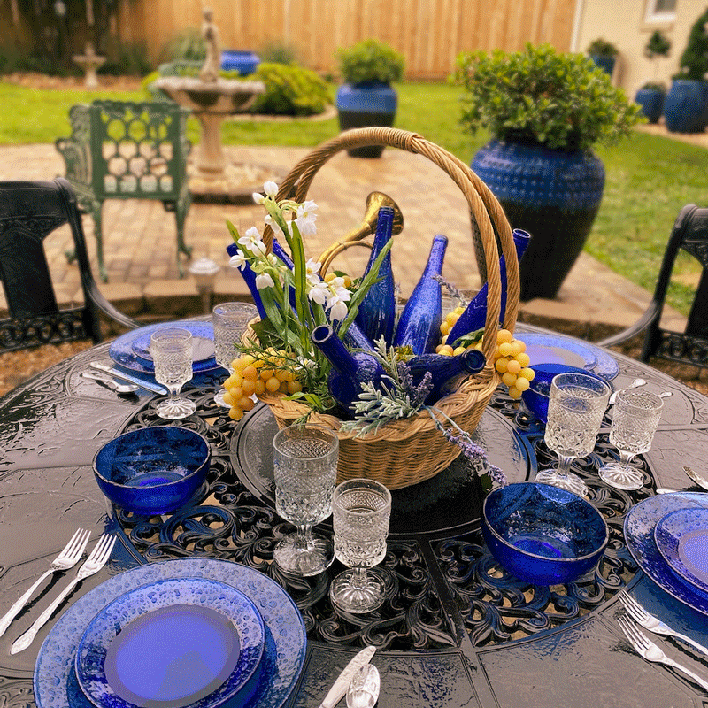 A table in a garden set with blue glassware